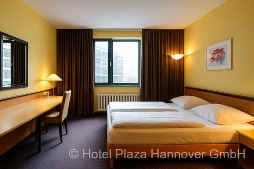 Doppelzimmer in warmen Farbtönen mit braunen Gardinen und Wänden, die halbhoch mit Holz verkleidet und darüber gelb gestrichen sind. Im Raum steht ein großer Schreibtisch mit einem großen Flachbild-TV darüber. Natürliches Licht fällt durch das Fenster herein.